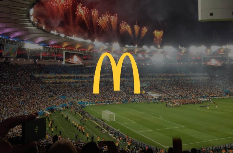 The McDonald's logo set against a packed football stadium with orange fireworks shooting up into a circle of black sky.