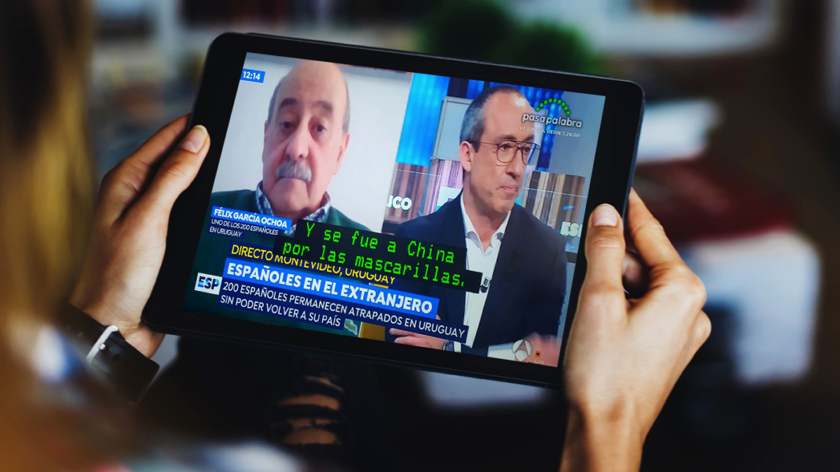 Hands holding a tablet showing a news report with Spanish subtitles.