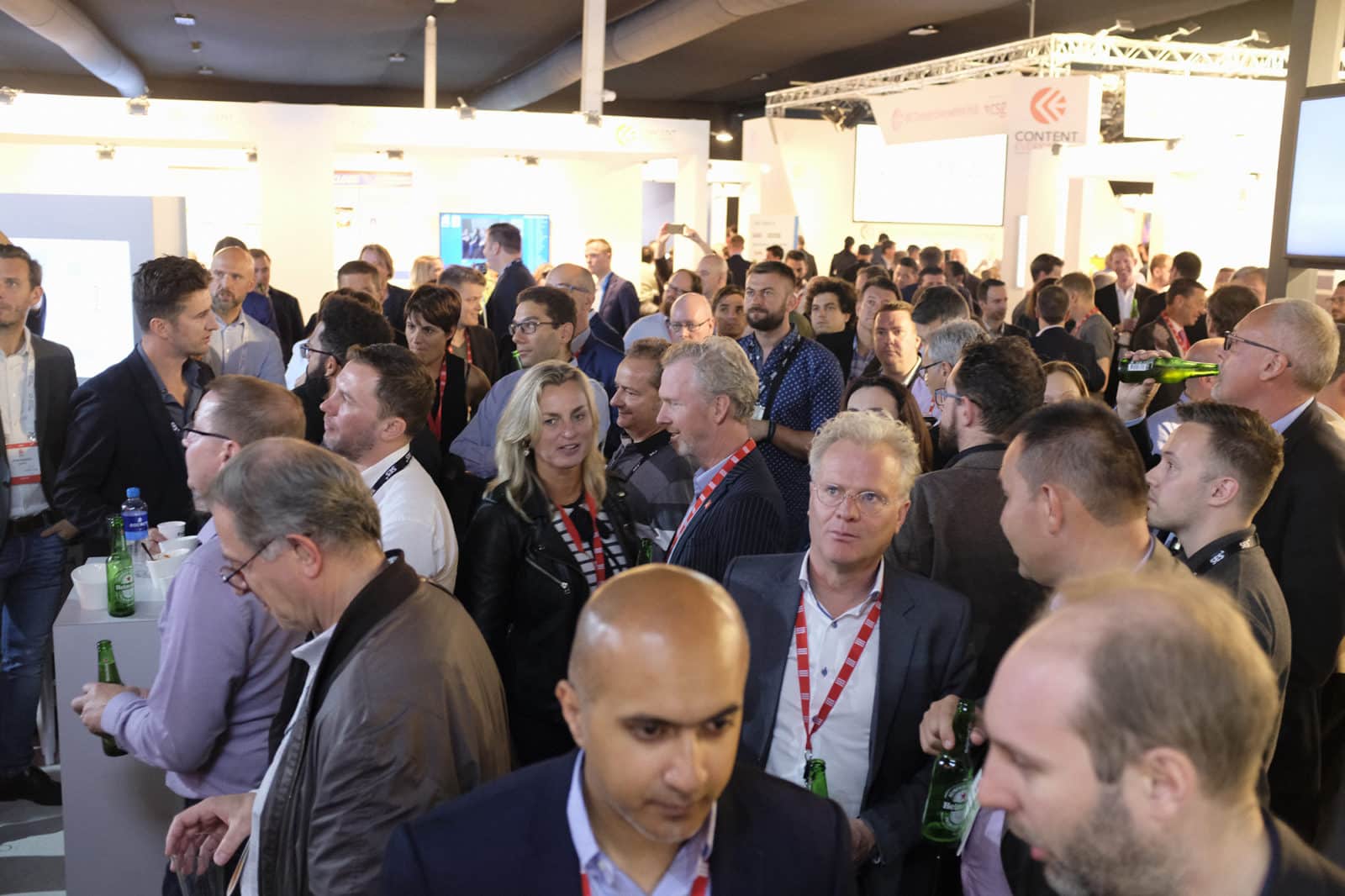 A large group of people gathered in a convention venue.