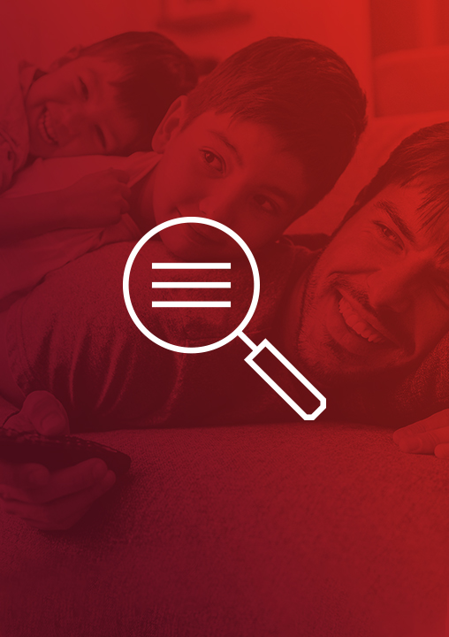 An icon of a magnifying glass. The icon is set against a red-tinged background featuring a grinning man holding a remote control and lying on his front with two smiling boys on his back.