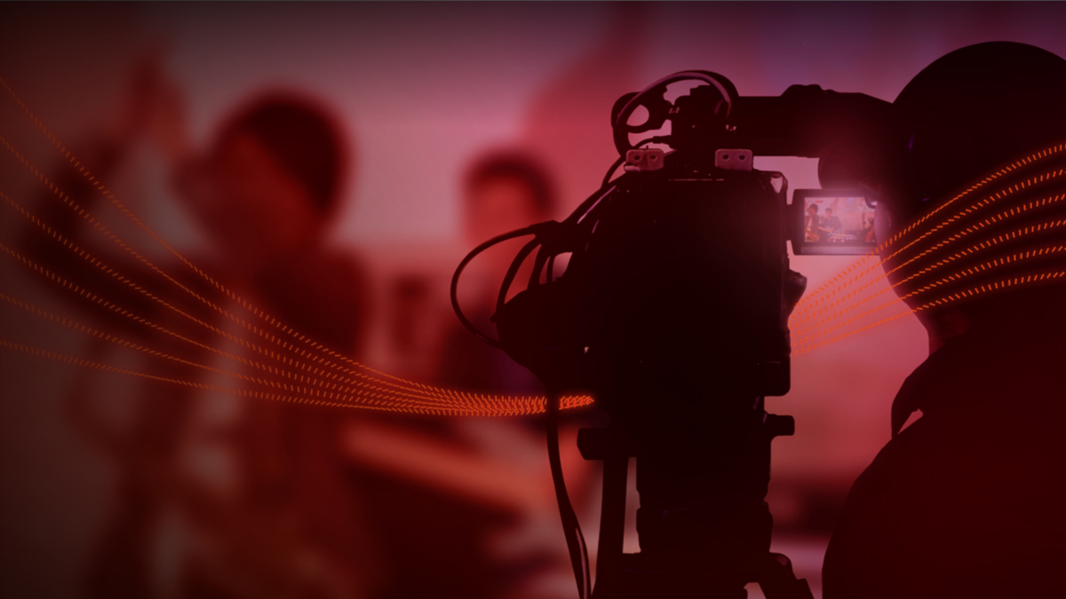 Red, dotted ribbons of light weaving between a camera operator and their camera.