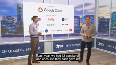 Two men standing in front of a screen displaying different companies' logos, including Red Bee's, in a television studio. A subtitle reading, 'Last year, we had 32 speakers and of course they each gave us...' is displayed at the bottom of the screen.