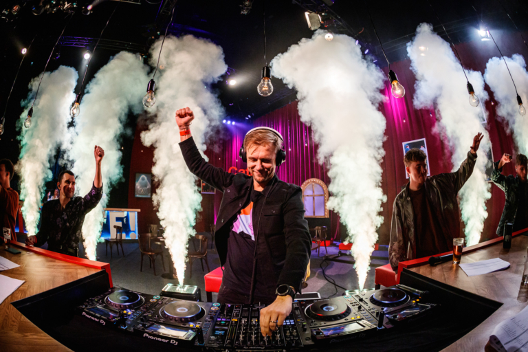 A DJ with clouds of smoke erupting behind him.