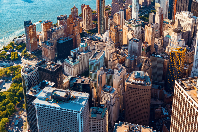 A bird's eye view of high-rise buildings in a city overlooking a body of water.