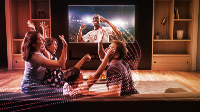 Six pink, red and white, dotted lines curving around a family celebrating in front of a TV. A grinning footballer with his fists raised is displayed on the TV.