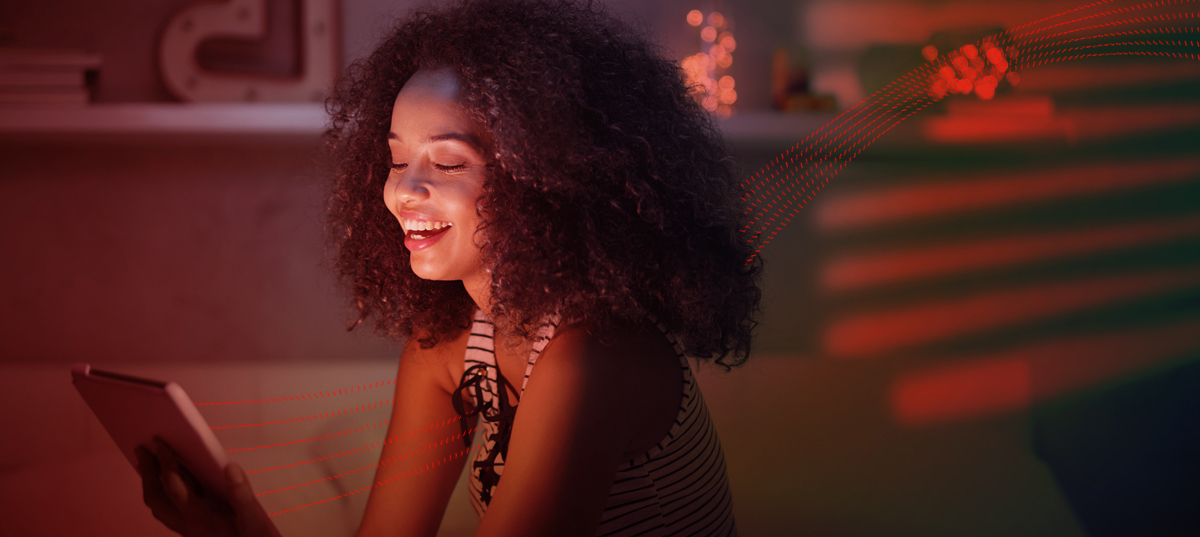 Six red, dotted lines moving past a beaming woman watching something on a tablet device.