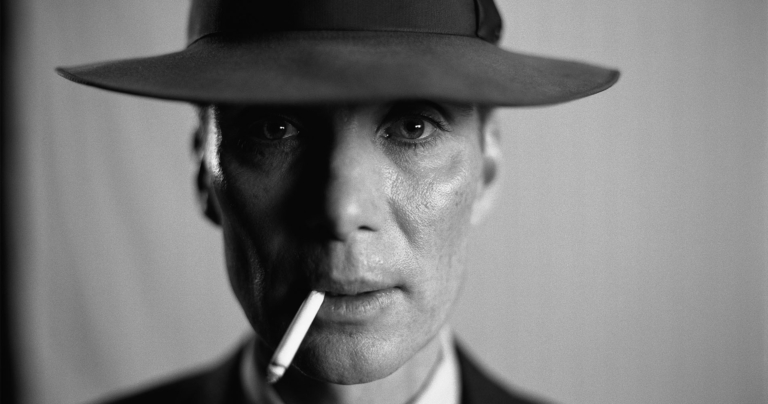 Black and white image of Cillian Murphy as J. Robert Oppenheimer wearing a hat and with a cigarette in his mouth.