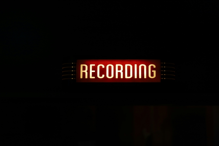 A glowing neon sign indicating the process of recording the audio description